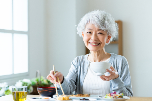 入れ歯治療をして美味しく食事をいただく女性